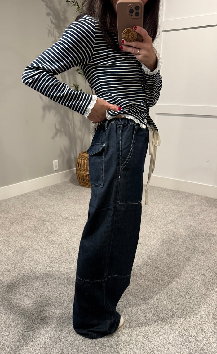 Person wearing a striped sweater and dark jeans in a room with a neutral color scheme.